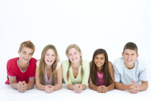 Five friends lying down in a row smiling